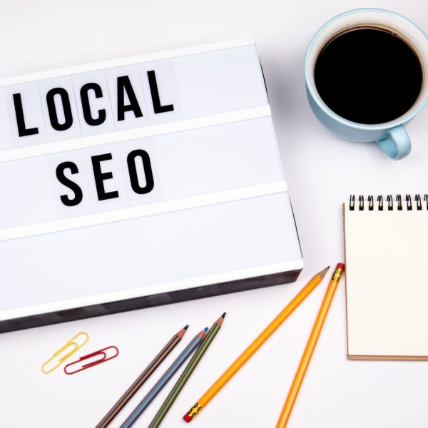 A white table with the sign "Local SEO", pencils, coffee, and notebook.