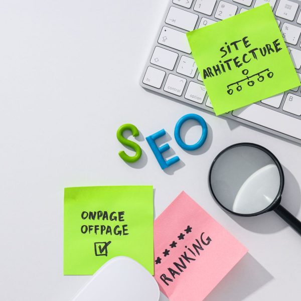 notes with words, SEO letters, keyboard, and magnifying glass on a white table