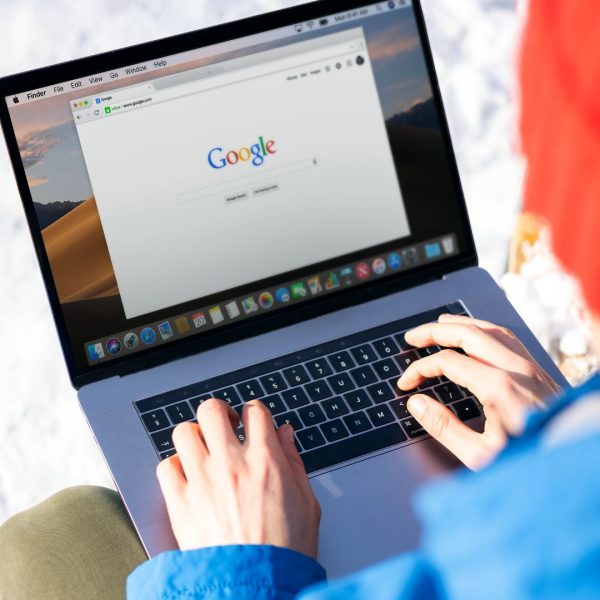 Person Using Macbook Pro with Google Website on Screen